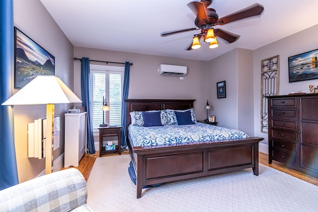 bedroom with ceiling fan, light hardwood / wood-style flooring, and a wall mounted AC