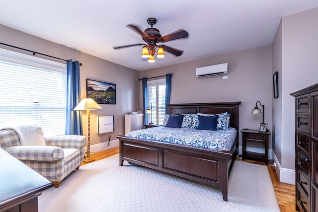 bedroom with a wall mounted air conditioner, ceiling fan, and light wood-type flooring