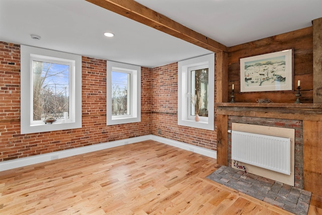 unfurnished living room with brick wall, light hardwood / wood-style floors, and radiator