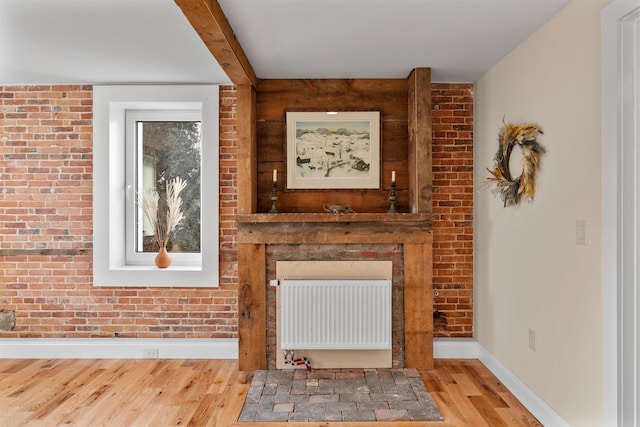 unfurnished living room featuring light hardwood / wood-style floors, radiator, and brick wall