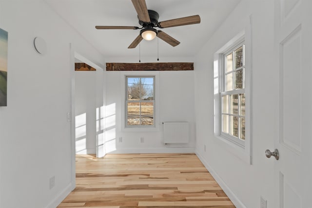 unfurnished room with light hardwood / wood-style flooring, radiator, a healthy amount of sunlight, and ceiling fan