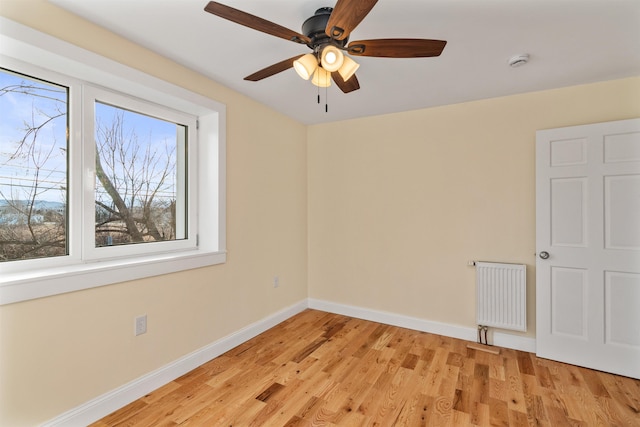 empty room with radiator heating unit, light hardwood / wood-style flooring, and ceiling fan