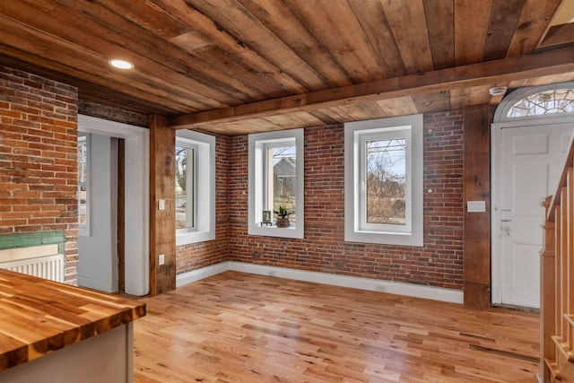 interior space with wooden ceiling, light hardwood / wood-style flooring, and brick wall