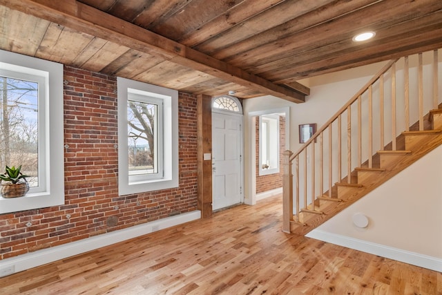 foyer featuring wood ceiling, light hardwood / wood-style flooring, beamed ceiling, and brick wall