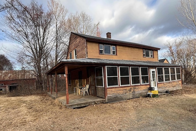 rear view of house featuring a wooden deck and a sunroom