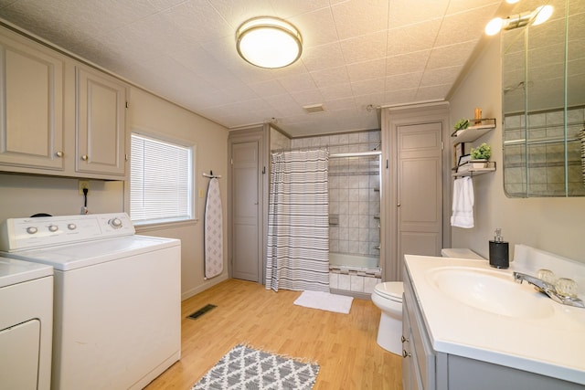 full bathroom featuring hardwood / wood-style floors, vanity, toilet, shower / bathtub combination with curtain, and washing machine and clothes dryer