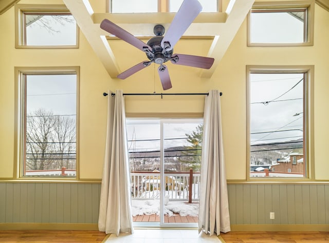 doorway with ceiling fan and wooden walls