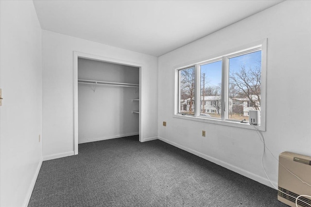 unfurnished bedroom with dark colored carpet and a closet