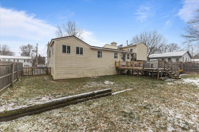 snow covered rear of property featuring a lawn and a deck