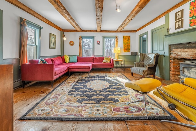 interior space featuring beam ceiling, a wealth of natural light, and a wood stove