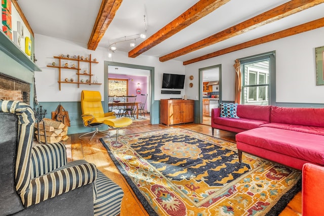 living room with track lighting, beam ceiling, and light hardwood / wood-style flooring