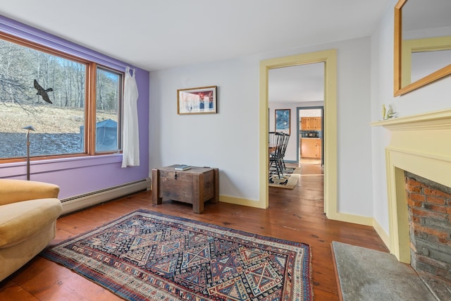 living area with a fireplace, a baseboard radiator, and wood-type flooring