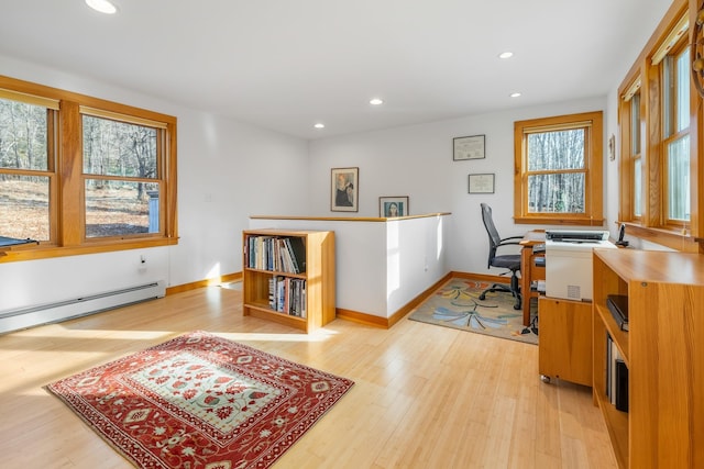 home office with a baseboard radiator, a wealth of natural light, and light hardwood / wood-style flooring