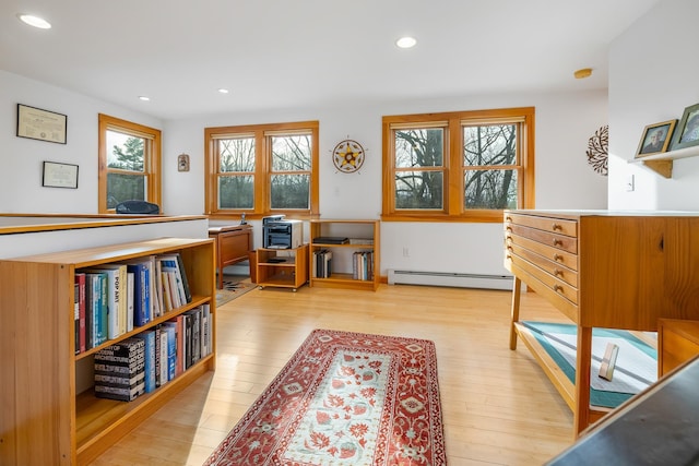 sitting room with a baseboard heating unit and light hardwood / wood-style flooring