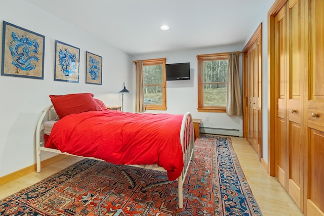 bedroom with a baseboard radiator and light hardwood / wood-style flooring