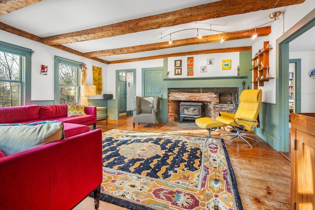 living room featuring hardwood / wood-style floors, beam ceiling, and a wood stove