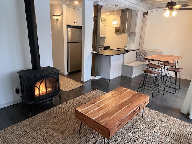 living room featuring a wood stove, ceiling fan, and dark hardwood / wood-style flooring