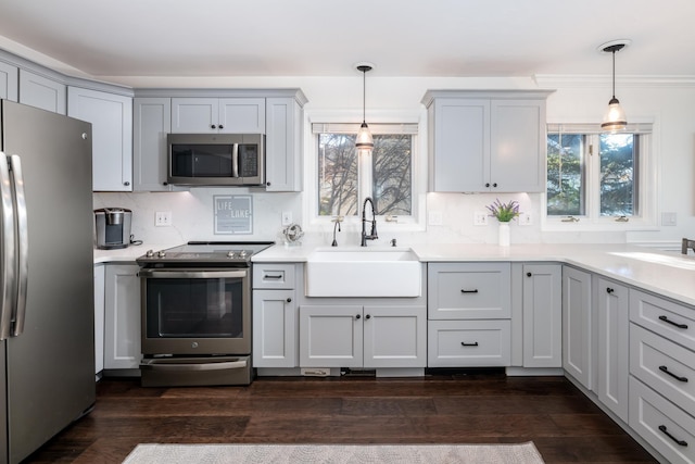 kitchen featuring dark wood-type flooring, sink, pendant lighting, and appliances with stainless steel finishes