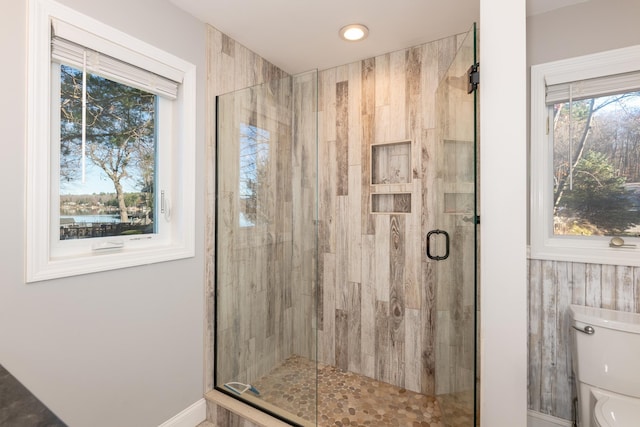 bathroom featuring a shower with shower door and toilet