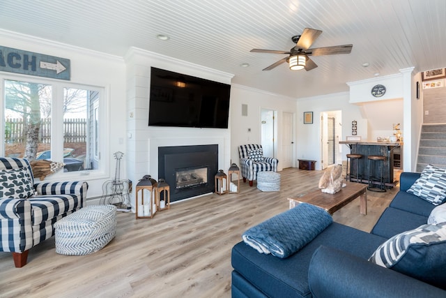 living room with ceiling fan, wooden ceiling, crown molding, a fireplace, and light wood-type flooring