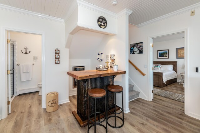 bar featuring light hardwood / wood-style floors, ornamental molding, and wood counters