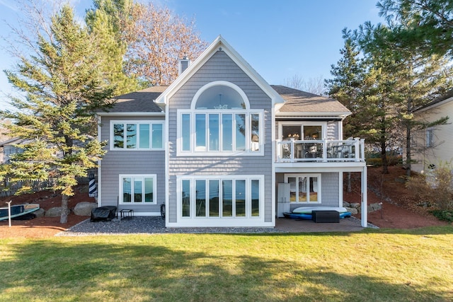 back of house with a lawn and a balcony