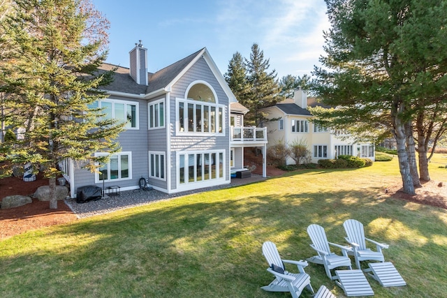 rear view of property with a lawn and a balcony