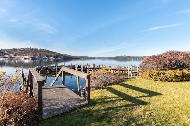 view of dock with a water view and a yard