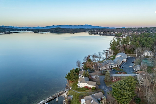 aerial view at dusk featuring a water and mountain view