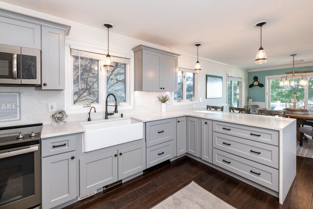 kitchen featuring gray cabinetry, sink, kitchen peninsula, pendant lighting, and range