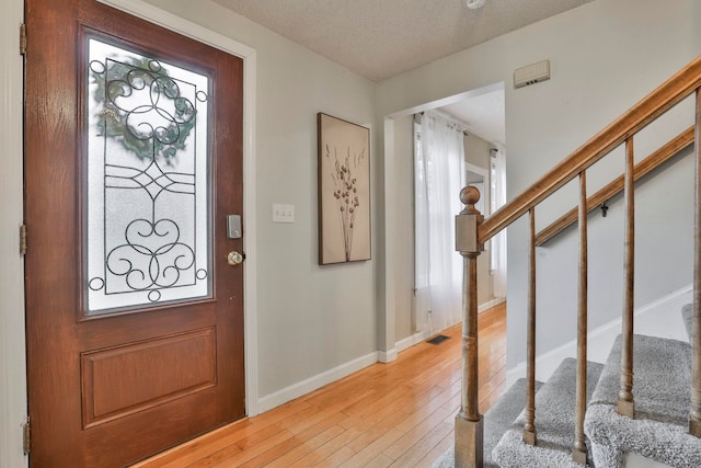 foyer entrance with a textured ceiling and light hardwood / wood-style floors