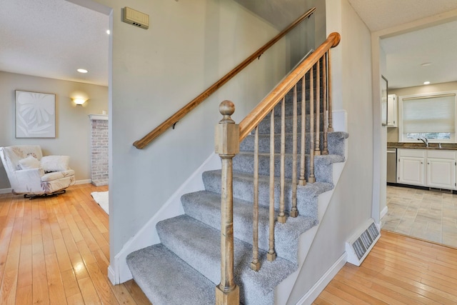 staircase with sink and wood-type flooring