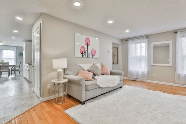 living room with light hardwood / wood-style floors, a textured ceiling, and a wealth of natural light