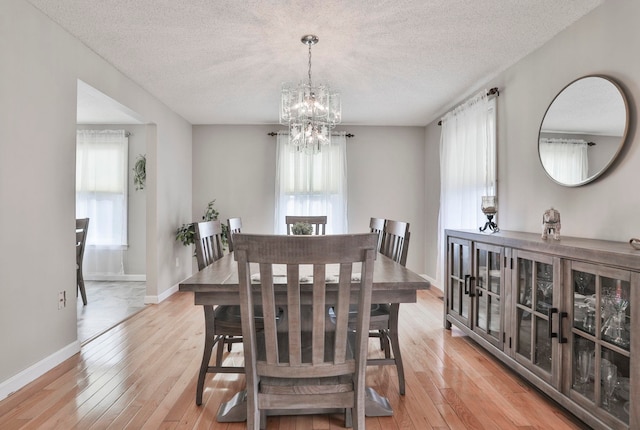 dining room featuring a notable chandelier, a textured ceiling, and light wood-type flooring