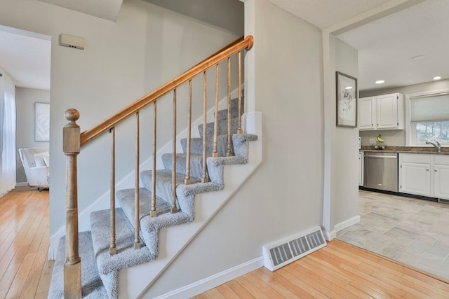 stairway with hardwood / wood-style floors and sink