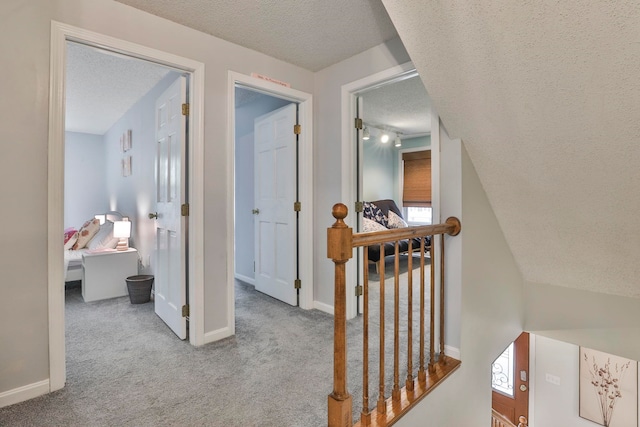 hall with light colored carpet and a textured ceiling