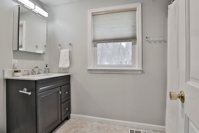 bathroom with tile patterned flooring, vanity, and a textured ceiling