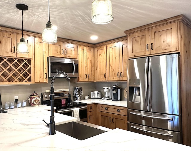 kitchen with decorative light fixtures, stainless steel appliances, light stone counters, and sink