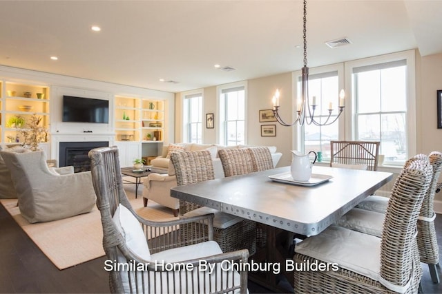 dining area with built in shelves, a notable chandelier, and hardwood / wood-style floors