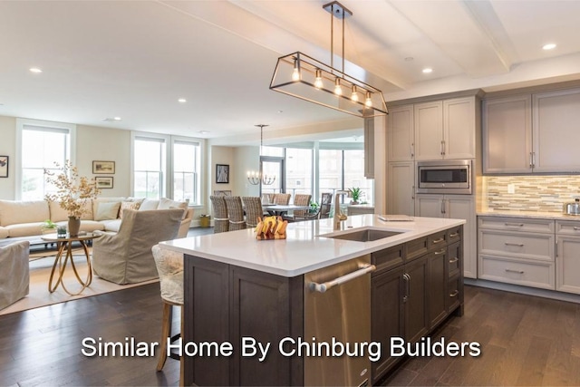 kitchen with appliances with stainless steel finishes, a center island with sink, decorative light fixtures, and sink