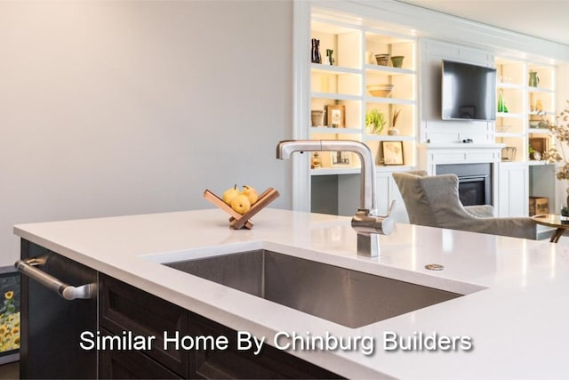 kitchen with sink, a large fireplace, and stainless steel dishwasher