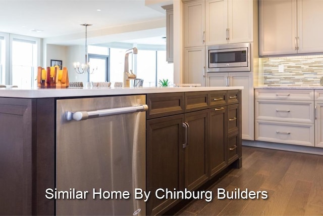 kitchen featuring pendant lighting, appliances with stainless steel finishes, dark wood-type flooring, decorative backsplash, and a chandelier