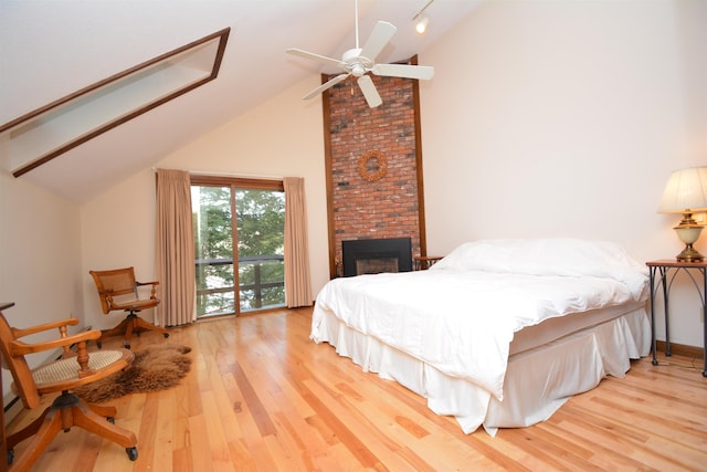 bedroom with a brick fireplace, ceiling fan, vaulted ceiling, and hardwood / wood-style flooring