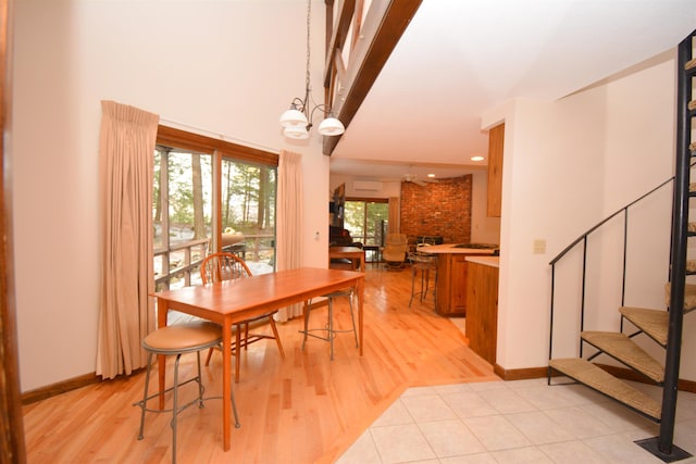 dining room with light hardwood / wood-style floors, a towering ceiling, and an inviting chandelier