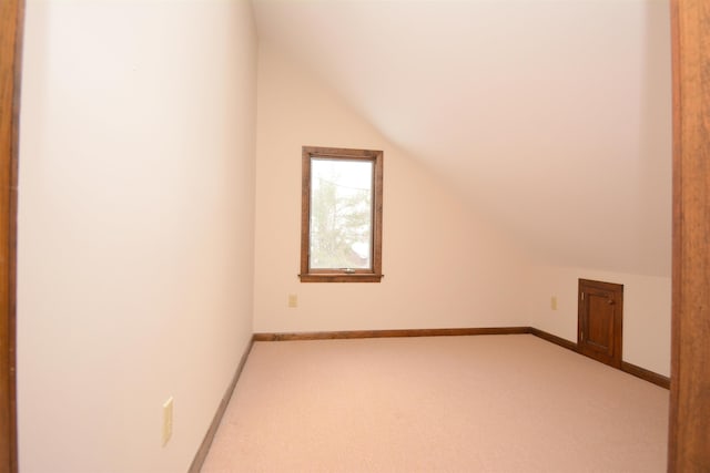 additional living space featuring light carpet and vaulted ceiling