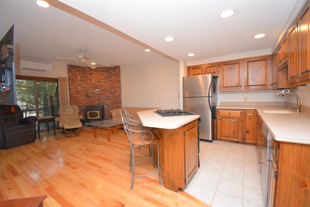 kitchen with a wood stove, sink, a kitchen island, a kitchen bar, and stainless steel appliances