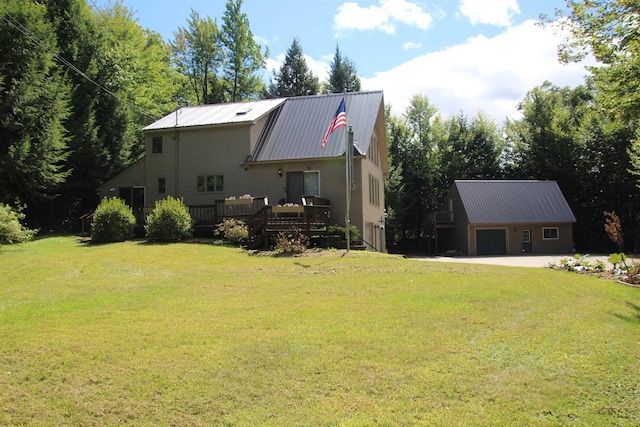 exterior space with a garage, a wooden deck, an outbuilding, and a lawn