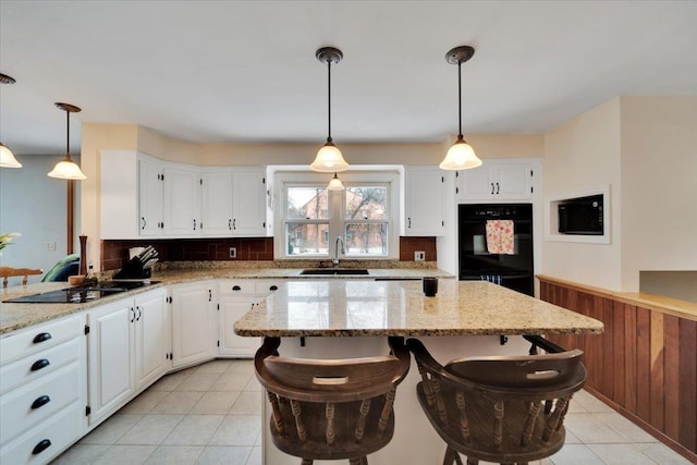 kitchen featuring white cabinets, a kitchen bar, sink, and hanging light fixtures