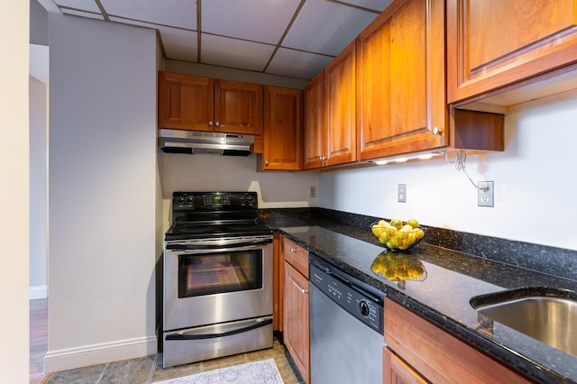 kitchen with a paneled ceiling, sink, stainless steel appliances, and dark stone counters