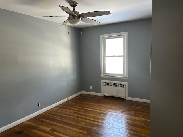 spare room with ceiling fan, dark wood-type flooring, and radiator